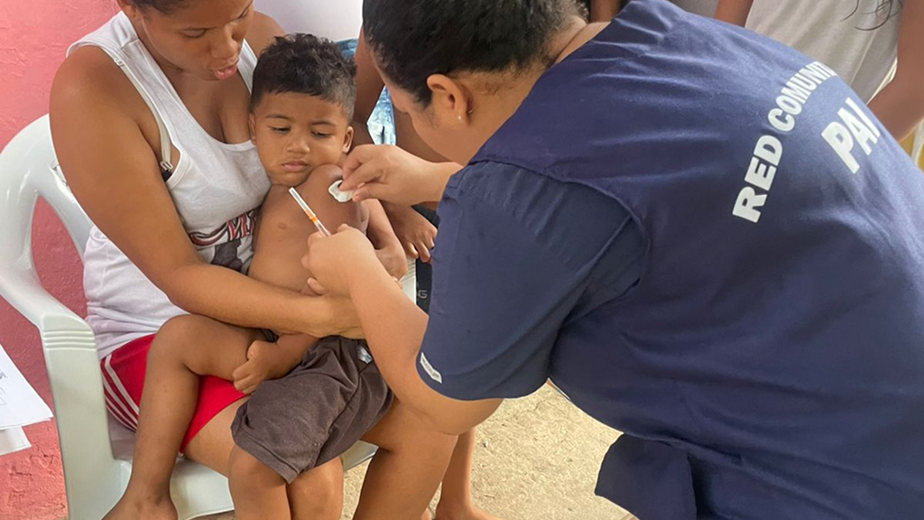 Niño en brazos de su madre recibiendo una vacuna