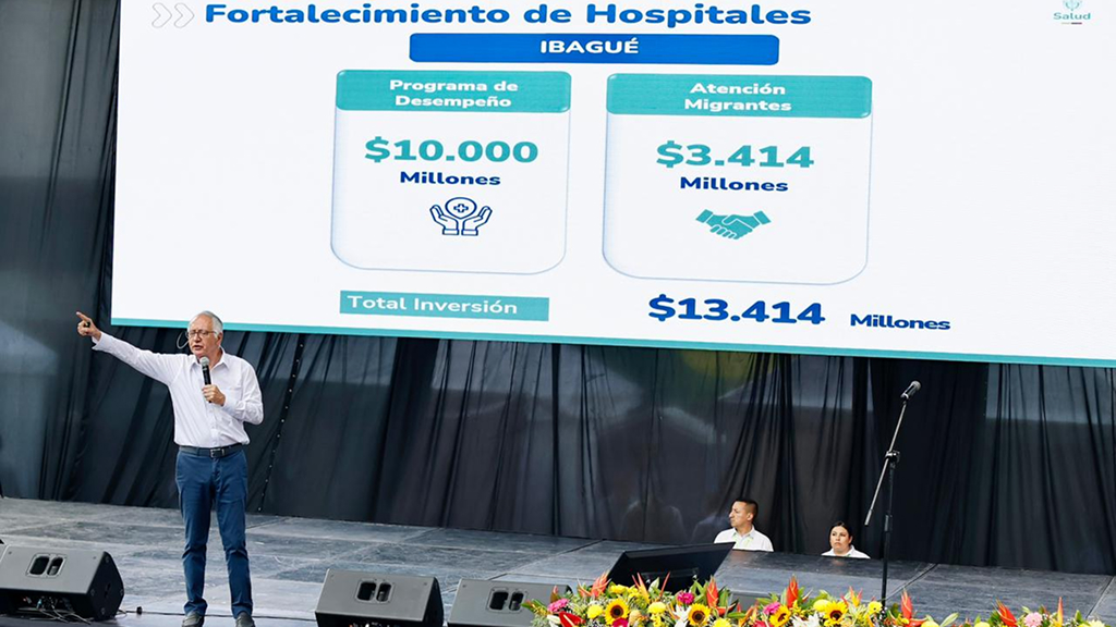 Ministro de Salud en tarima con diapositiva de cifras de fortalecimiento de hospitales en la tarima de rendición de cuentas